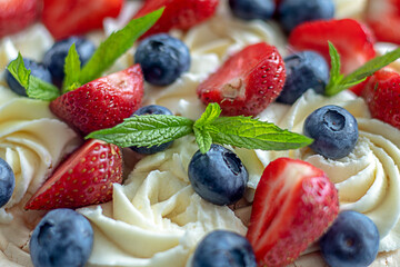 Meringue cake background with strawberries and blueberries, mint pourings.