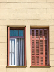 Two windows with brown shutters, one open and the other closed. Some space for text and logo.