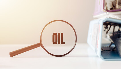 A magnifying glass highlights the word Oil against a blurry office background.