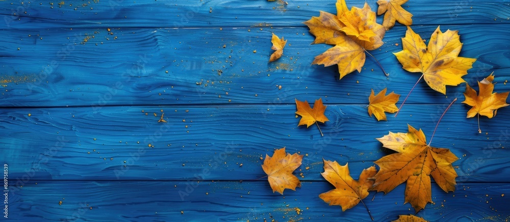 Poster autumn-themed scene with yellow maple leaves on a blue wooden surface. seen from above with space fo
