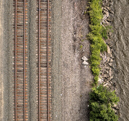 view of train tracks next to river from kingston rhinebeck bridge in hudson valley (railroad line near water near mountains) curve in track turning trains looking down new york state transport commute