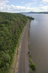 view of train tracks next to river from kingston rhinebeck bridge in hudson valley (railroad line near water near mountains) curve in track turning trains looking down new york state transport commute