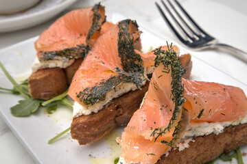 herbed salmon lox on toast with cream cheese (breakfast gravlax open faced sandwiches) arugula lemon drizzle (dill crust fish with herbs) toast bread toasted fork plate brunch restaurant meal seafood