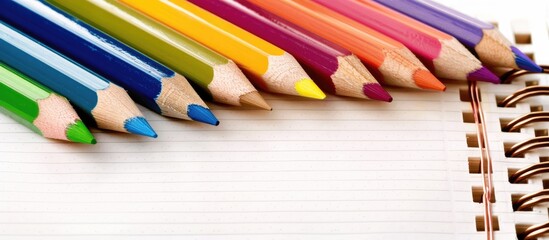 Obraz premium Various colored pencils arranged on a blank notebook page with copy space image.
