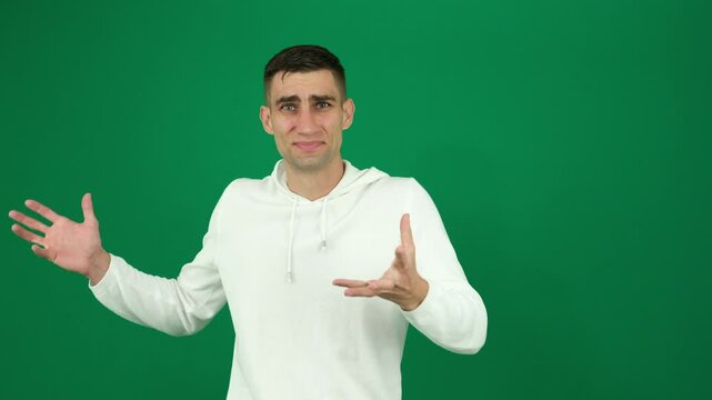 Disgust man. emotions of a handsome man guy on a green background chromakey close-up dark hair young man Young hispanic man standing, wearing shirt