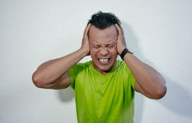 Asian man showing stress expression. Angry and mad face of Asian man in green t-shirt on isolated background