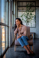 Full length of an attractive african american woman relaxing in an armchair by the window