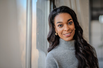 Close-up of an african-american woman standing at the window and smiling