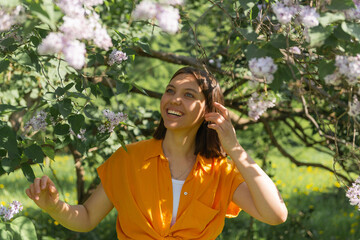 Young smiling girl portrait outdoors, posing at beautiful blooming trees at sunlight