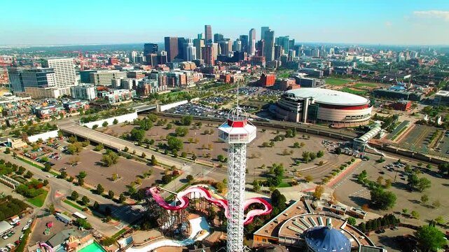 Aerial Shot Of Ball Arena By Modern Financial District In City, Drone Flying Backwards By Observation Tower On Sunny Day - Denver, Colorado