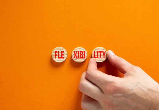 Flexibility symbol. Concept word Flexibility on beautiful wooden circles. Businessman hand. Beautiful orange background. Business flexibility concept. Copy space.