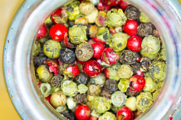Vibrant mix of red, green, and black peppercorns inside a jar.