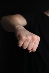 Man showing fist with space for tattoo on black background, closeup