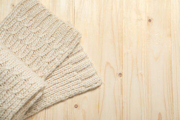 Knitted scarf on wooden table, top view. Space for text