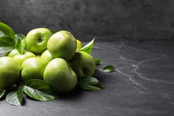 Ripe green apples with leaves on dark grey table. Space for text