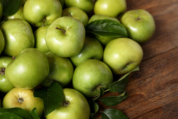 Ripe green apples with leaves on wooden table, closeup