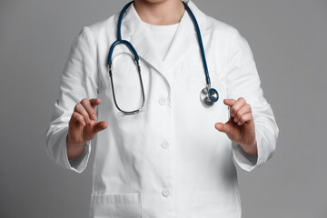 Doctor holding something on grey background, closeup
