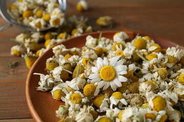 Dry and fresh chamomile flowers on table, closeup