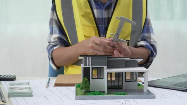 Professional architect team and engineer discuss about architectural project on meeting table with safety helmet, wooden block and architectural document scatter around. Closeup. Delineation.