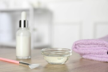Peeling procedure. Bottle of chemical peel, bowl with liquid, towel and brush on wooden table indoors. Space for text
