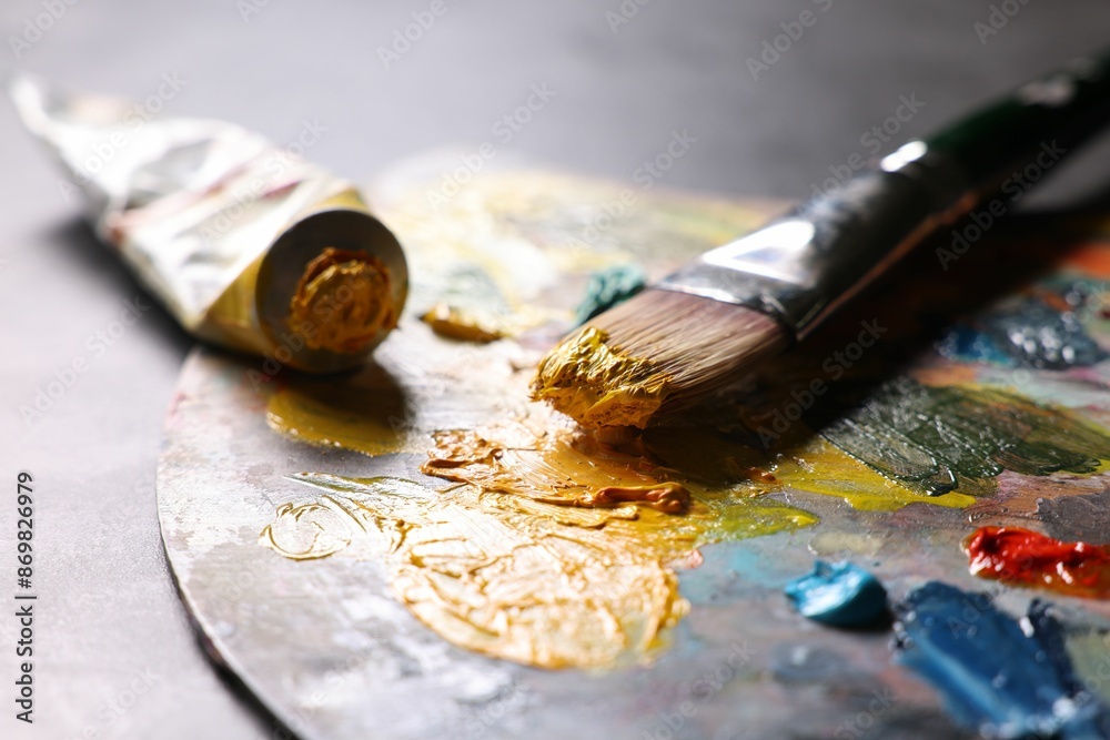 Wall mural Artist's palette, brush and paints on grey table, closeup