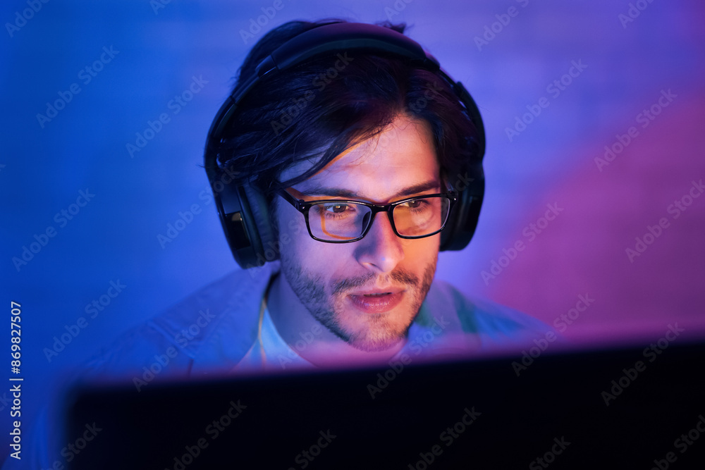 Poster this image shows a man wearing headphones and glasses, sitting in front of a computer screen. he is 