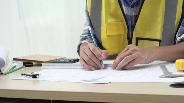 Professional architect team and engineer discuss about architectural project on meeting table with safety helmet, wooden block and architectural document scatter around. Closeup. Delineation.