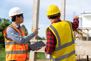 A team of construction engineers talks with managers and construction workers at the construction site. Quality inspection, plans, home and industrial building design projects