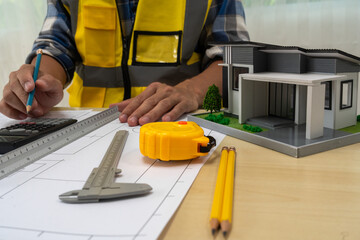 Professional team of architects and engineers discuss architectural project on conference table with hard hats, wooden blocks and architectural documents scattered around. Close-up. Drawing.