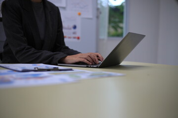 Young happy professional business woman employee sitting at desk working on laptop in modern corporate office interior. Smiling female worker using computer technology typing browsing web.