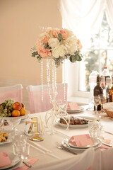 Wedding reception table setting with white tablecloth, pink flowers, and a table number
