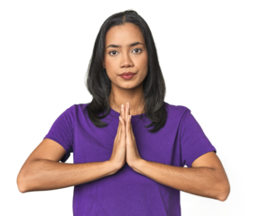 Young Latina posing in studio praying, showing devotion, religious person looking for divine inspiration.