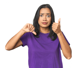 Young Latina posing in studio showing thumbs up and thumbs down, difficult choose concept