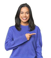Simple portrait of a young Latina smiling and pointing aside, showing something at blank space.