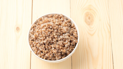 buckwheat porridge in a round white plate on a wooden table.