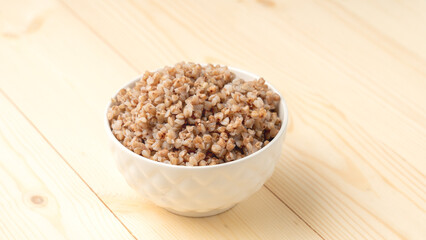 buckwheat porridge in a round white plate on a wooden table.