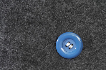 Hand sewing a button to a gray thick fabric