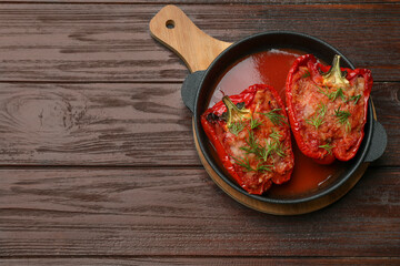 Tasty stuffed peppers in dish on wooden table, top view. Space for text