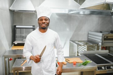 African American male chef standing at kitchen counter in restaurant kitchen, copy space