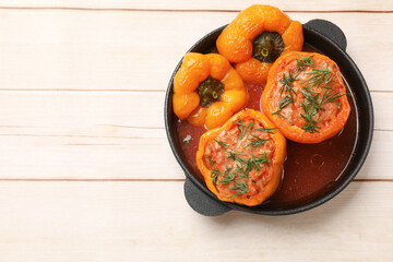 Tasty stuffed peppers in pan on light wooden table, top view. Space for text