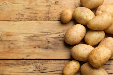 Many fresh potatoes on wooden table, top view. Space for text