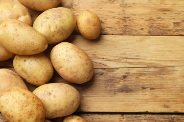 Many fresh potatoes on wooden table, top view. Space for text