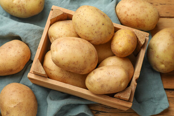 Many fresh potatoes in crate on wooden table, above view