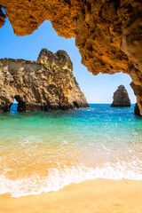 Small paradise beach vertically photographed from inside the rocks near Portimao, Algarve, Portugal