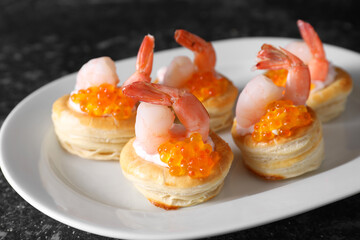 Delicious puff pastry with shrimps, cream cheese and red caviar on dark table, closeup