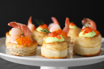 Different delicious puff pastry snacks on stand