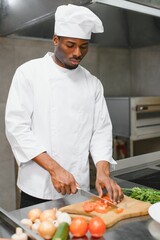 Portrait of happy African American male chef standing in restaurant kitchen