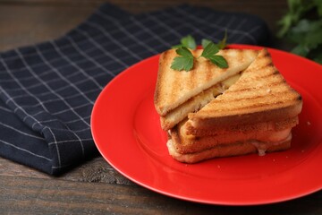 Pieces of toasted bread with melted cheese and parsley on wooden table, closeup