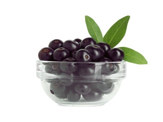 Fresh ripe acai berries in glass bowl and green leaves isolated on white