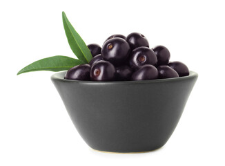 Fresh ripe acai berries in bowl and green leaves isolated on white